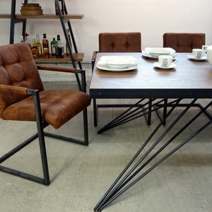 May include: A brown leather dining chair with a black metal frame and a table with a wooden top and black metal legs. The table has a white ceramic serving dish and two white ceramic plates with white saucers and cups.