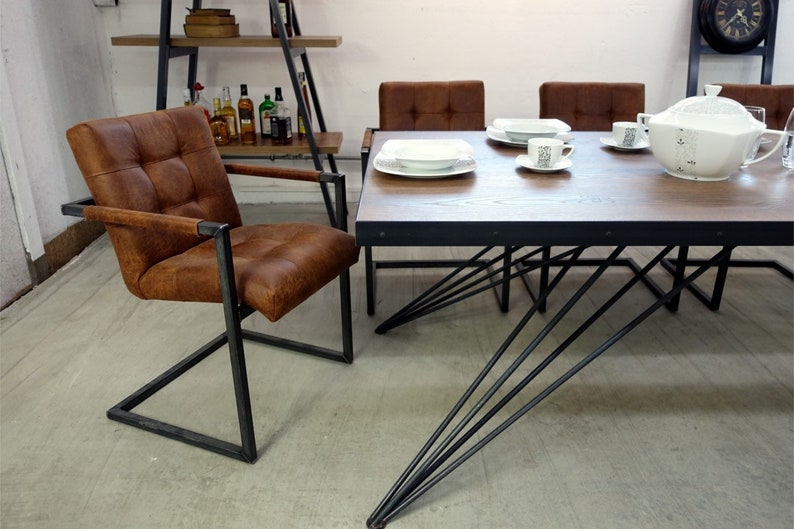 May include: A brown leather dining chair with a black metal frame and a table with a wooden top and black metal legs. The table has a white ceramic serving dish and two white ceramic plates with white saucers and cups.