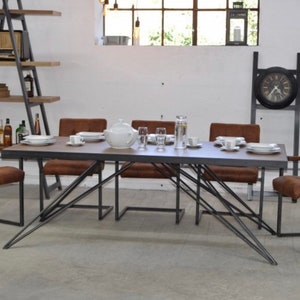 May include: A rustic dining table with a dark wood top and a metal frame. The table is surrounded by six brown leather chairs with metal frames. The table is set with plates, glasses, and a teapot.