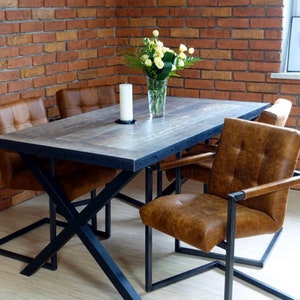 May include: A rustic dining table with a wood top and black metal legs. Four chairs with brown leather upholstery surround the table. A vase with white flowers sits on the table.