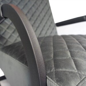 Puede incluir: Un sill&oacute;n tapizado en gris con un tejido de patr&oacute;n de diamante. El sill&oacute;n tiene brazos de metal negro y una base de metal negro.