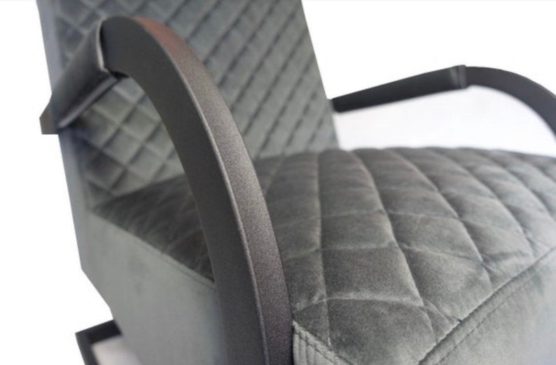 Puede incluir: Un sill&oacute;n tapizado en gris con un tejido de patr&oacute;n de diamante. El sill&oacute;n tiene brazos de metal negro y una base de metal negro.