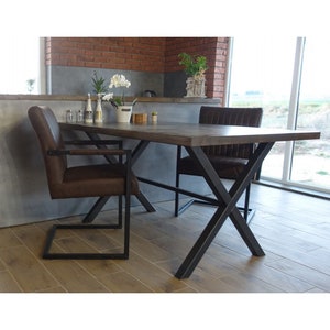 May include: A brown leather dining chair with a black metal frame and a wooden table with a black metal X-shaped base.