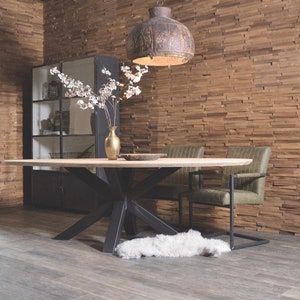 May include: A large oval wooden dining table with a black metal base and a starburst design. Two green upholstered chairs with black metal frames are placed at the table. A white faux fur rug is on the floor. The wall behind the table is covered in wood paneling.