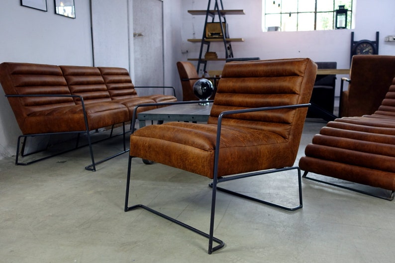 May include: A set of brown leather chairs with black metal frames. The chairs have a tufted design and are arranged in a living room setting.