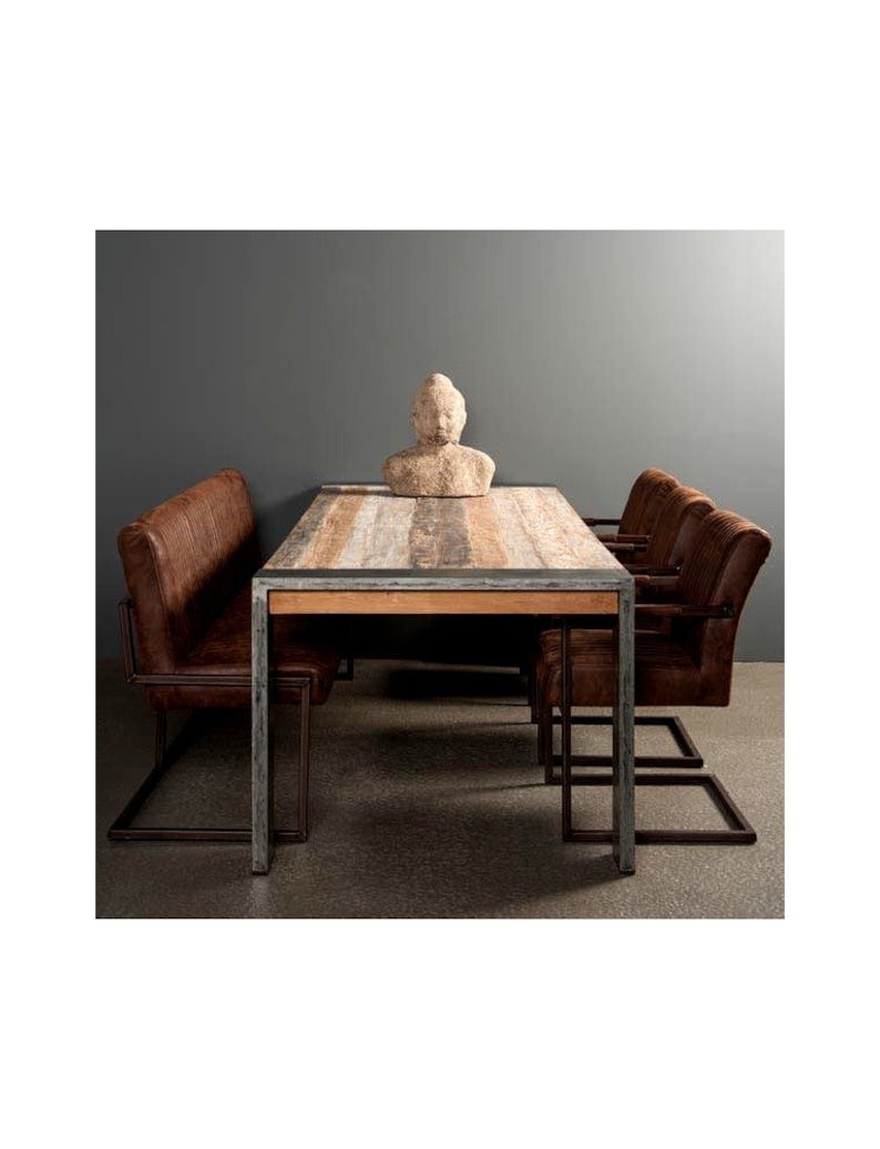 May include: A rustic wooden dining table with a metal frame and four brown leather chairs. A small stone sculpture sits on the table.