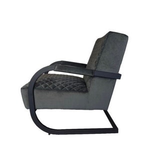 Puede incluir: Un sill&oacute;n negro con tapicer&iacute;a de terciopelo gris acolchado y estructura de metal negro. El sill&oacute;n tiene un respaldo y brazos curvos.