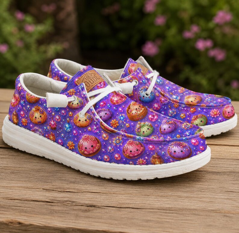 K&ouml;nnte beinhalten: Ein Paar Slipper mit einem leuchtend violetten Hintergrund, der ein wiederkehrendes Muster aus kleinen, bunten, runden Kreaturen und funkelnden Sternen zeigt. Die Schuhe haben wei&szlig;e Schn&uuml;rsenkel, wei&szlig;e Sohlen und einen hellbraunen Aufn&auml;her.