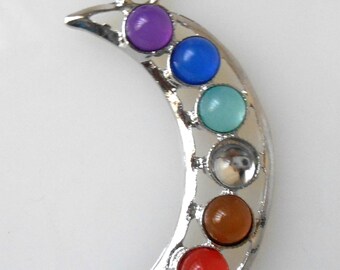 May include: A silver crescent moon pendant with seven colorful gemstones. The stones are purple, blue, light blue, white, brown, orange, and red.