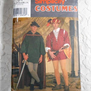 May include: Simplicity Costumes sewing pattern for two men's Renaissance costumes. The pattern includes a green tunic with a cape and a red tunic with a doublet. The pattern is for sizes XS, S, M, L, and XL.