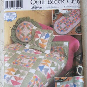 May include: Quilt Block Club Lesson #6 Double Wedding & Dutchman's Puzzle sewing pattern. The pattern includes instructions for making a quilt, pillows, and table runners. The quilt is made with a variety of fabrics in shades of green, pink, blue, and yellow.