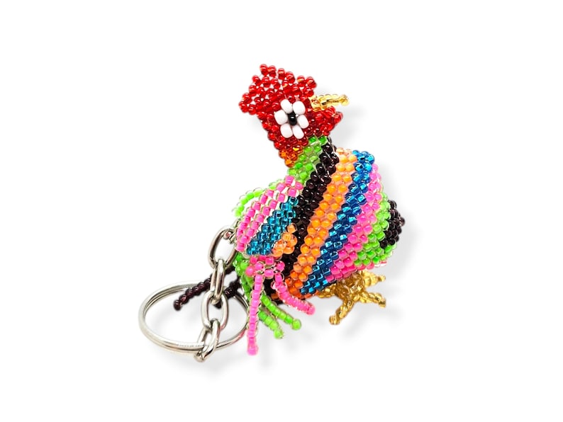 May include: A colorful beaded rooster keychain with a silver key ring. The rooster is made of small, colorful beads in shades of red, orange, yellow, green, blue, and purple. The rooster has a black eye and a gold beak.