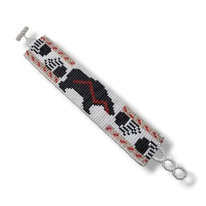 May include: A white beaded bracelet with a black bear design and red accents. The bracelet has a simple clasp.