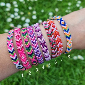 May include: Eight colorful friendship bracelets with different patterns, including pink, purple, green, orange, and blue. The bracelets are numbered 1 through 8.