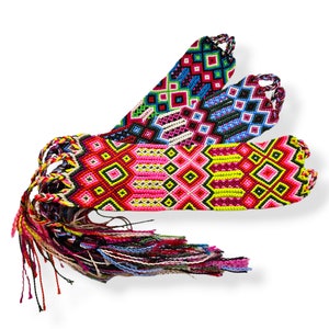 May include: Three colorful friendship bracelets with geometric patterns in pink, yellow, green, blue, and black. The bracelets are made with woven thread and have long tassels.