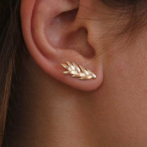 May include: Gold leaf shaped earrings. The earrings are small and delicate, and they are a great way to add a touch of elegance to any outfit.