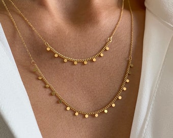 May include: A gold chain necklace with two layers of delicate chains and small round charms hanging from each layer.