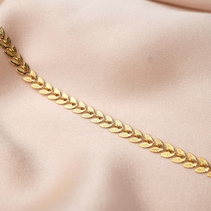 May include: A gold chain necklace featuring a delicate leaf design. The chain is made up of small, interconnected leaves, creating a flowing, elegant look.