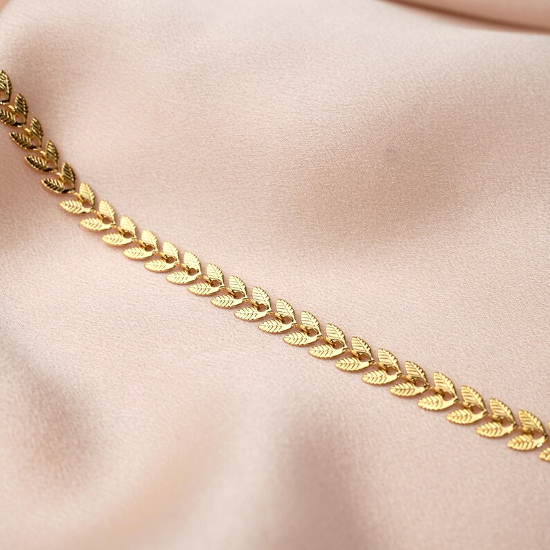 May include: A gold chain necklace featuring a delicate leaf design. The chain is made up of small, interconnected leaves, creating a flowing, elegant look.