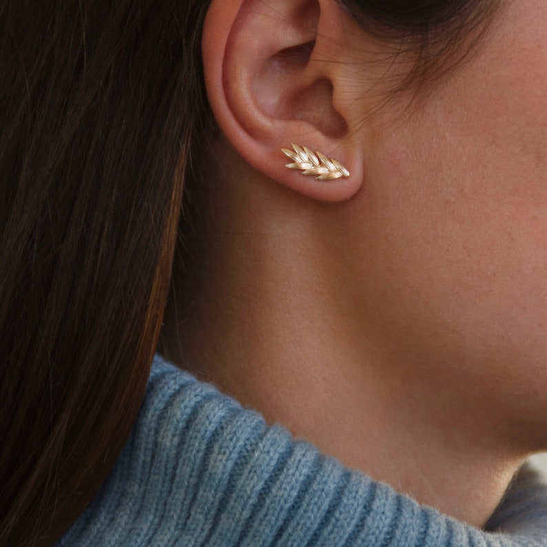 May include: Gold leaf shaped earrings. The earrings are small and delicate, and they are a great way to add a touch of elegance to any outfit.