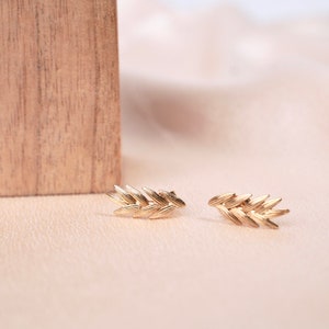 May include: A pair of gold wheat-shaped earrings. The earrings are made of a delicate, intricate design and are perfect for adding a touch of elegance to any outfit.