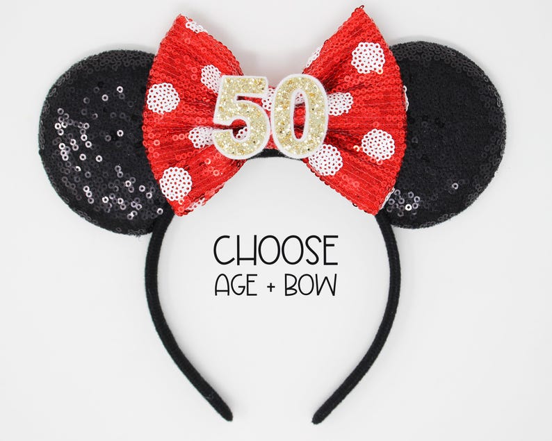 May include: A black sequined headband with two round ears and a red sequined bow featuring white polka dots. The center of the bow displays the number 50 in gold glitter. The text CHOOSE AGE + BOW is printed in black below the bow on the headband.