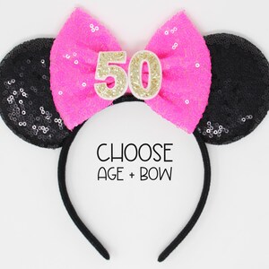 May include: A black headband with two round black sequined ears and a bright pink sequined bow in the center. The bow features the number 50 in gold glitter. The text CHOOSE AGE + BOW is printed in black in the center of the headband.