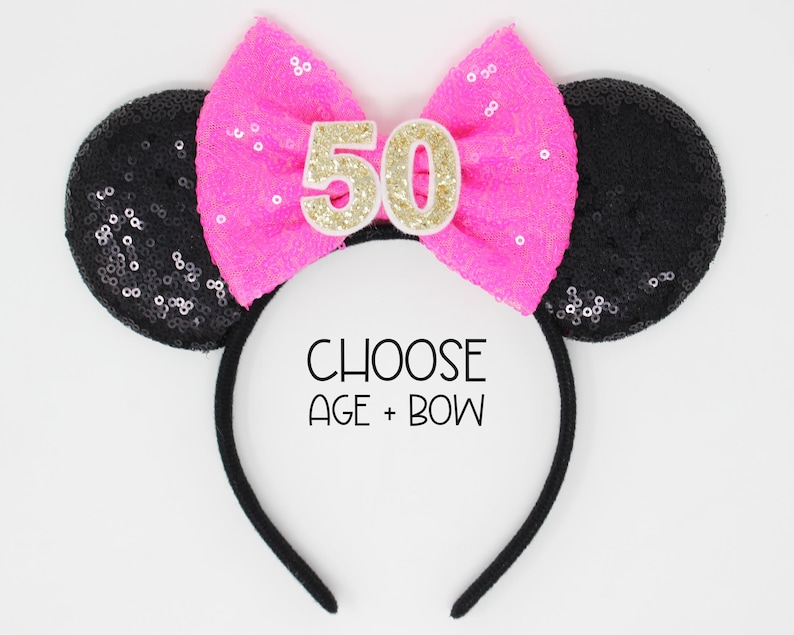 May include: A black headband with two round black sequined ears and a bright pink sequined bow in the center. The bow features the number 50 in gold glitter. The text CHOOSE AGE + BOW is printed in black in the center of the headband.
