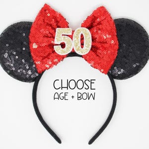 May include: A black headband with two round black sequined ears and a large red sequined bow in the center. The bow features the number 50 in gold glitter. The text CHOOSE AGE + BOW is printed in black on the headband between the ears.