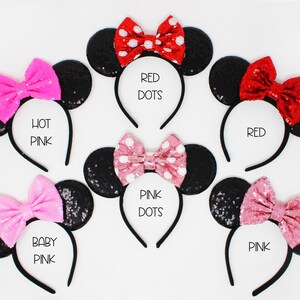 May include: Six black sequin mouse ear headbands with different colored bows. The bows are red with white polka dots, hot pink, pink with white polka dots, baby pink, red, and pink. The headbands are labeled with the bow colors.