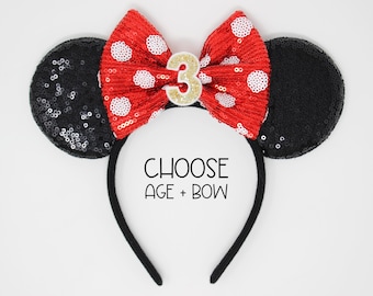 May include: Black sequin Minnie Mouse ears headband with a red and white polka dot bow and a gold number 3. CHOOSE AGE + BOW.