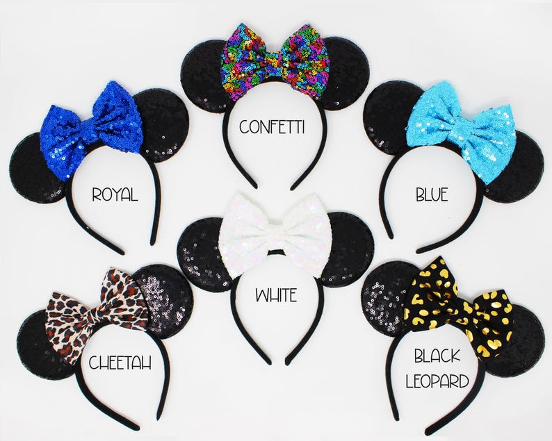 May include: Six pairs of black mouse ears with different colored bows. The bows are confetti, royal blue, blue, white, cheetah print, and black leopard print. The ears are on headbands.