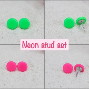 May include: A set of neon green and pink stud earrings. The earrings are round and have a simple design.  "Neon stud set" is written in pink letters on a white background.