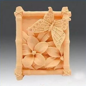 May include: A beige silicone mold with a raised design of a butterfly and flowers. The mold is shaped like a rectangle with a bamboo frame.