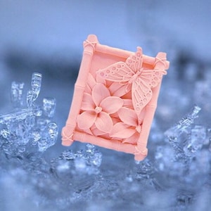 May include: A pink soap bar with a butterfly and flower design in a bamboo frame.