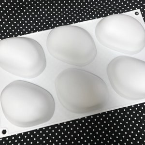 Puede incluir: Molde de silicona blanco con seis cavidades ovaladas. El molde est&aacute; dise&ntilde;ado para hacer jab&oacute;n, chocolate u otras golosinas.