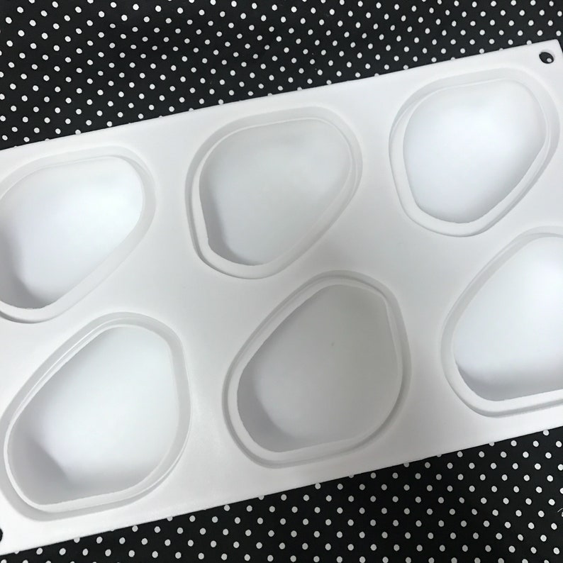 Puede incluir: Molde de silicona blanco con seis cavidades de forma irregular. El molde est&aacute; dise&ntilde;ado para hacer peque&ntilde;os pasteles u otros postres.