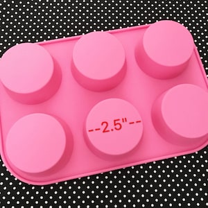 May include: Pink silicone mold with six round cavities, each measuring 2.5 inches in diameter. The mold is designed for making small cakes, cookies, or other treats.