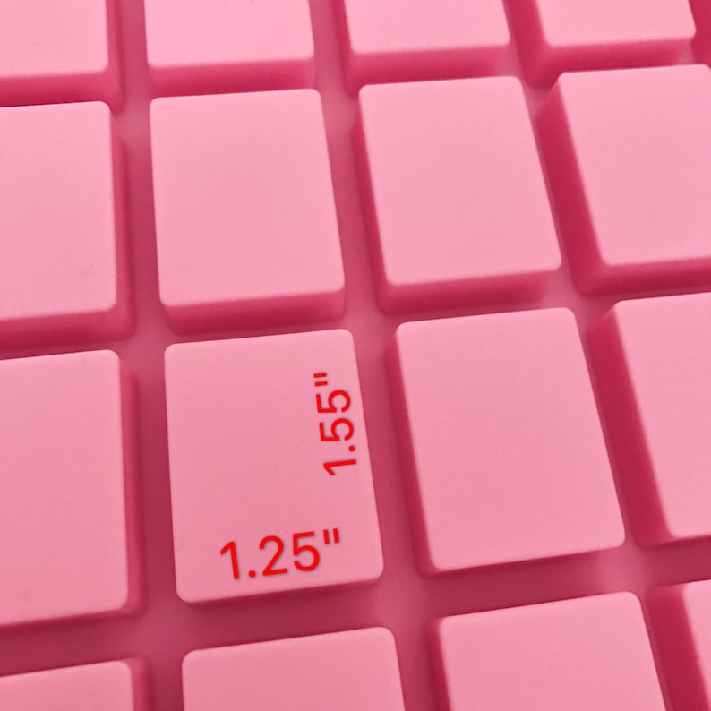 K&ouml;nnte beinhalten: Nahaufnahme einer rosa Silikonform mit rechteckigen Formen. Ein Rechteck hat die Ma&szlig;e "1,25"" und "1,55"" in rotem Text. Die Form ist f&uuml;r Bastelarbeiten oder zum Backen bestimmt.