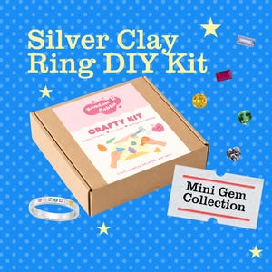 Peut inclure: Un kit de bricolage pour créer des bagues en argile argentée. La boîte en carton porte l'inscription "Silver Clay Ring DIY Kit" et "Crafty Kit". Une carte "Mini Gem Collection" et une bague finie sont également présentées. Le fond est bleu à pois blancs.