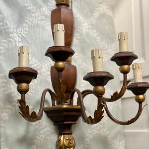May include: A wooden wall sconce with five candle-style light bulbs. The sconce has a gold leaf finish and ornate details.