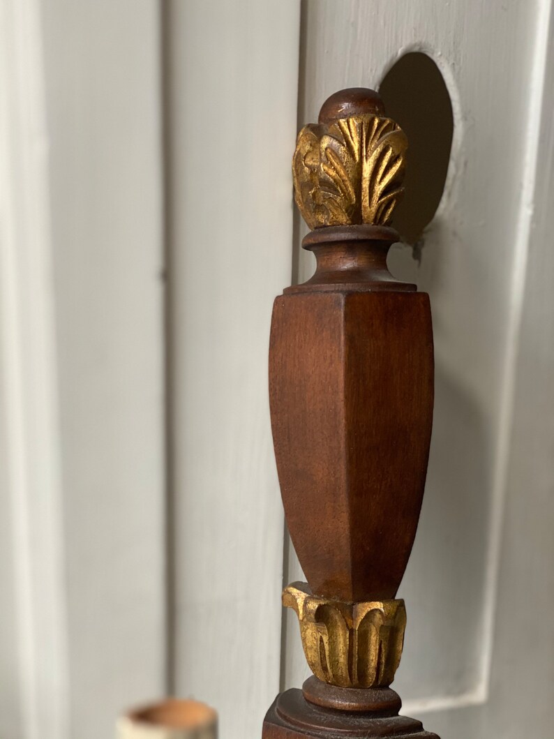 May include: A wooden finial with a gold leaf design. The finial is a decorative element often used on furniture.