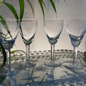 May include: Four clear glass wine glasses with a decorative etched pattern on a silver tray.