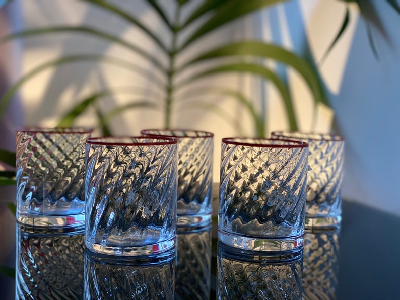 May include: Set of six clear glass tumblers with a textured, swirling design. Each tumbler has a thin red rim.