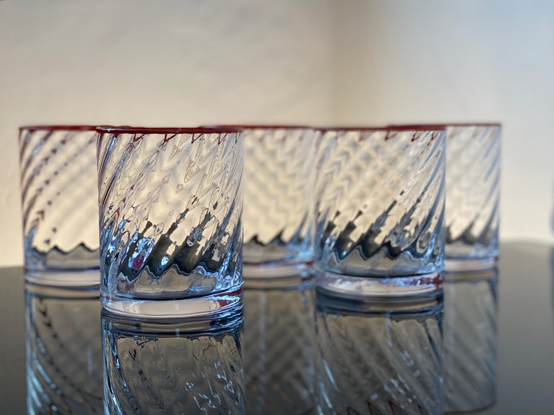 May include: Set of five clear glass tumblers with a red rim and a swirling, textured design.