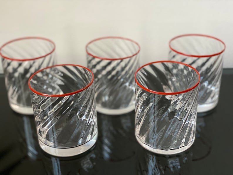 May include: Set of five clear glass tumblers with a red rim and a swirling pattern.