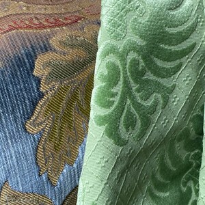 May include: Close-up of two fabric swatches. One is a green velvet with a damask pattern. The other is a multi-colored fabric with a woven design.