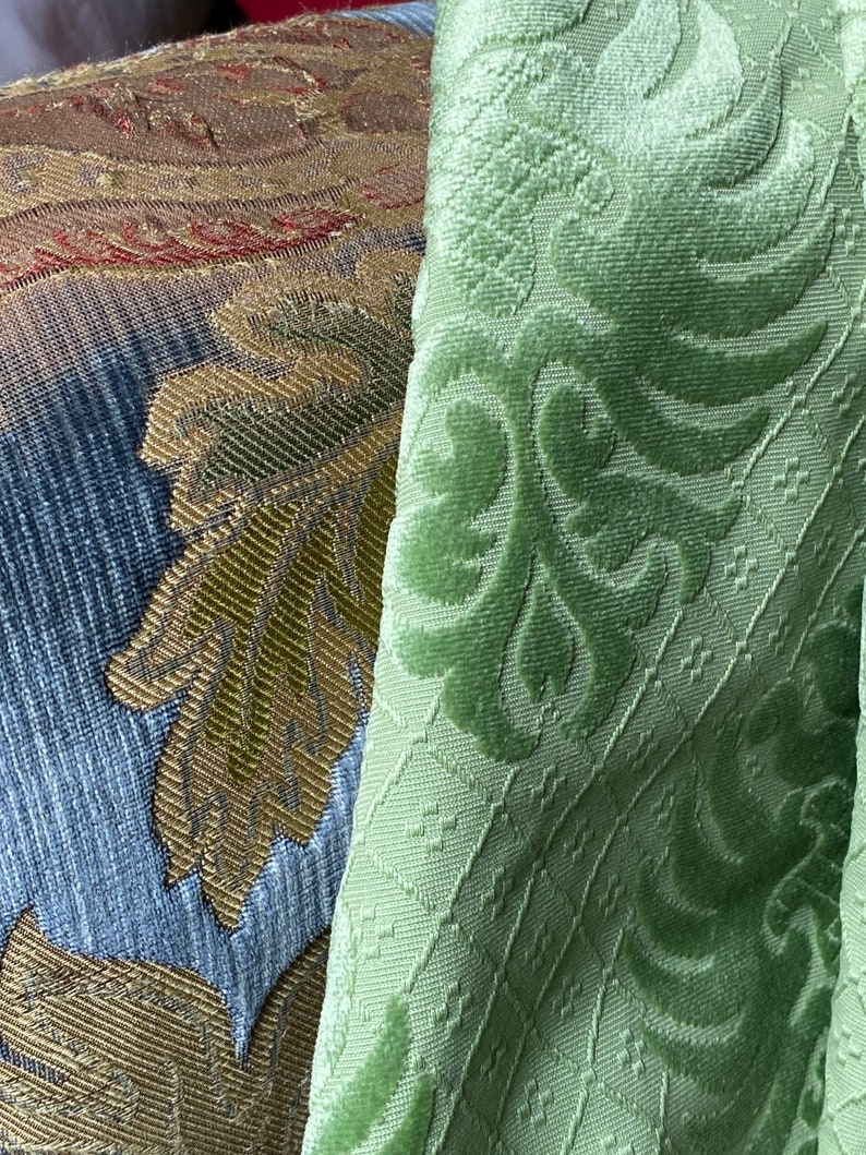 May include: Close-up of two fabric swatches. One is a green velvet with a damask pattern. The other is a multi-colored fabric with a woven design.