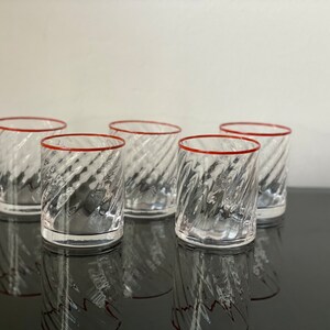 May include: Set of six clear glass tumblers with a red rim and a swirl pattern.