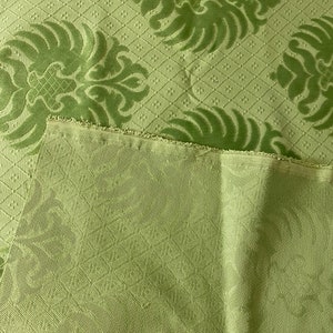 May include: Green fabric with a damask pattern. The fabric has a subtle sheen and a textured surface.